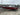 Red Tracker Pro V-175 fishing boat with Mercury motor on trailer, labeled OR 186 AFT, parked on lot under cloudy sky